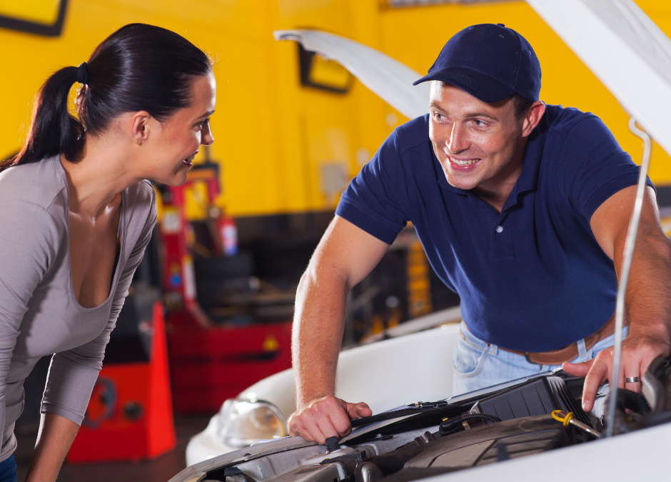 Male auto technician helping female customer